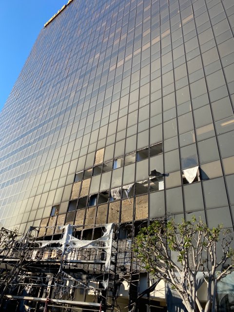 Outside of 25-story building with parts of lower 3 floors broken windows and burned through.
